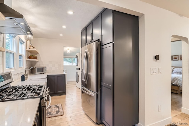 3219 S Washington St, Englewood, CO 80113 - kitchen with stainless steel appliances, open shelves, island range hood, light wood-style flooring, and arched walkways