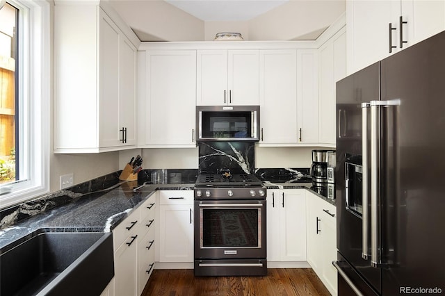 355 Steele St, Denver, CO 80206 - kitchen with stainless steel appliances, white cabinetry, dark wood-type flooring, a sink, and dark stone countertops