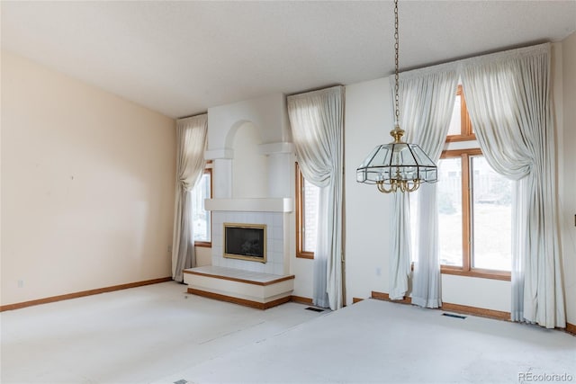 unfurnished living room featuring a tiled fireplace, a textured ceiling, and a notable chandelier