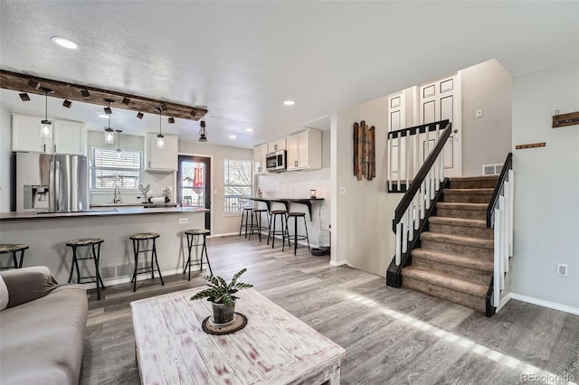 living room featuring hardwood / wood-style floors, beam ceiling, sink, and a textured ceiling