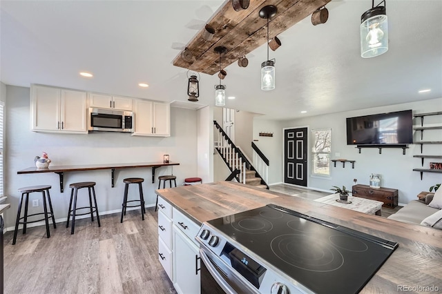 kitchen featuring butcher block counters, white cabinetry, hanging light fixtures, and appliances with stainless steel finishes