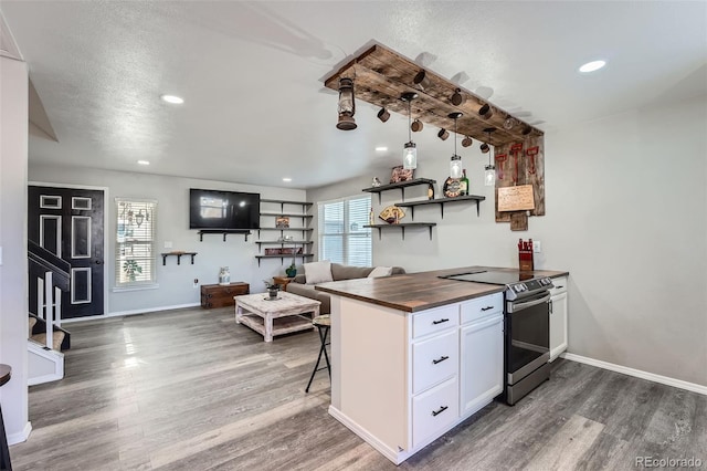 kitchen with dark wood-type flooring, wooden counters, white cabinets, electric stove, and a textured ceiling