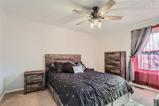 bedroom featuring a textured ceiling, light colored carpet, and ceiling fan