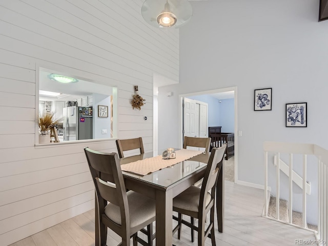 dining space with light wood-type flooring and a high ceiling