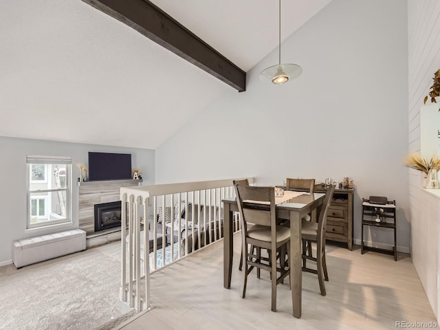 dining room featuring a fireplace, beamed ceiling, and high vaulted ceiling