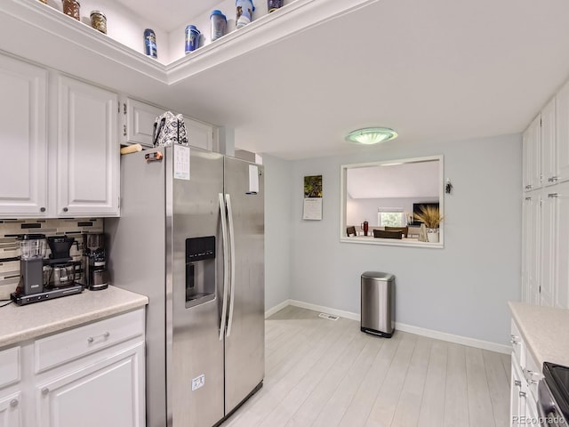 kitchen featuring appliances with stainless steel finishes, light hardwood / wood-style floors, white cabinetry, and tasteful backsplash