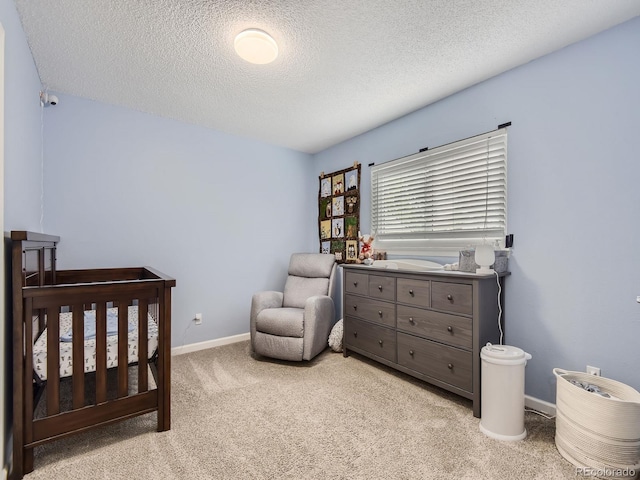 bedroom with a textured ceiling, light colored carpet, and a crib