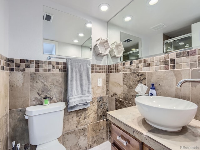 bathroom featuring tile walls, vanity, toilet, and a shower with door