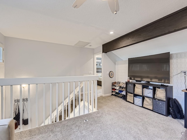 hallway with a textured ceiling, beam ceiling, and light carpet