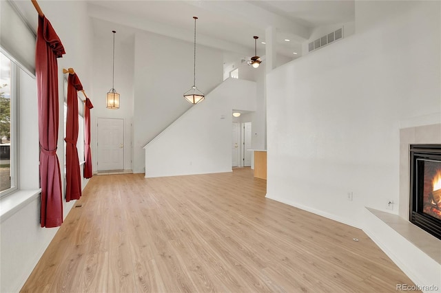 unfurnished living room featuring a fireplace, a towering ceiling, and a healthy amount of sunlight