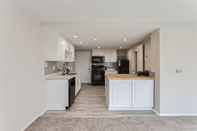 kitchen with sink, black appliances, kitchen peninsula, decorative backsplash, and white cabinets