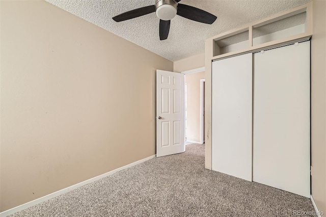 unfurnished bedroom with baseboards, carpet flooring, a closet, a textured ceiling, and a ceiling fan