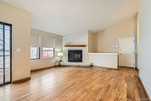 unfurnished living room featuring light wood-style flooring, a fireplace, baseboards, and lofted ceiling