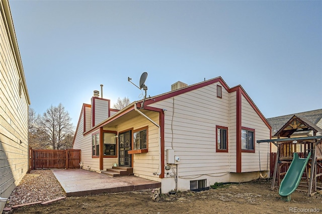 back of property with a patio, fence, a chimney, entry steps, and a playground