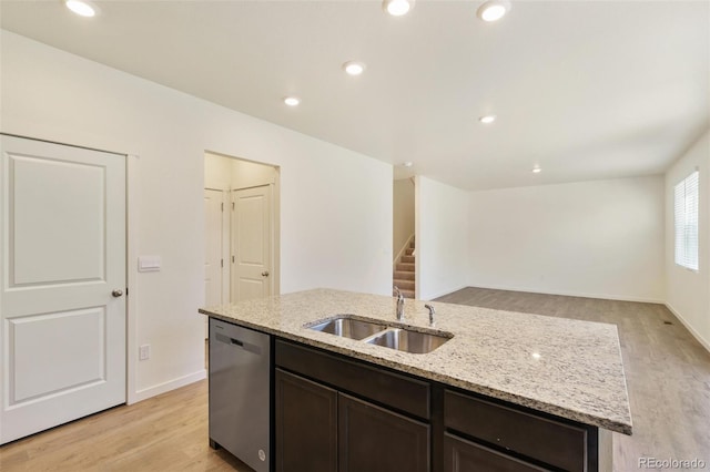 13467 Valentia St, Thornton, CO 80602 - kitchen featuring stainless steel dishwasher, light wood-style floors, a kitchen island with sink, dark brown cabinets, and light stone counters
