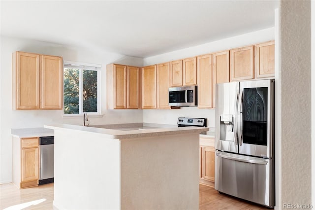 kitchen featuring light brown cabinets, appliances with stainless steel finishes, sink, a kitchen island, and light hardwood / wood-style floors