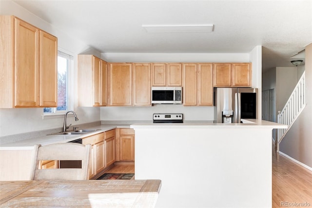 kitchen with sink, light wood-type flooring, light brown cabinetry, and stainless steel appliances