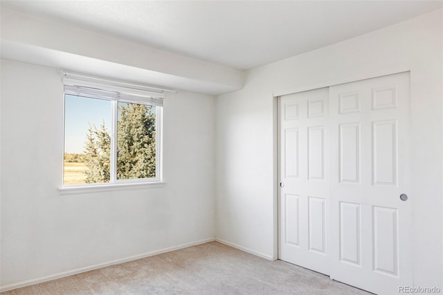 unfurnished bedroom with light carpet and a closet