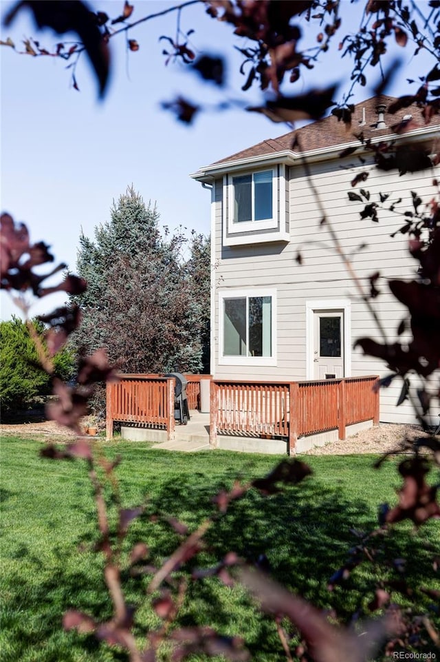 back of property featuring a deck and a lawn