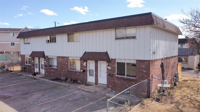 townhome / multi-family property featuring a shingled roof, mansard roof, and brick siding