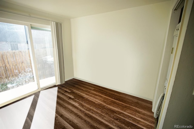 empty room with baseboards and dark wood-type flooring