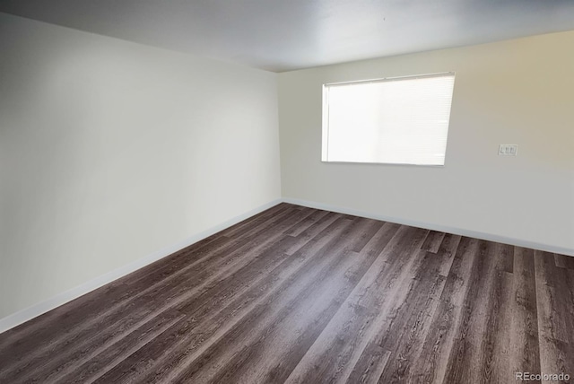 empty room featuring dark wood-style floors and baseboards