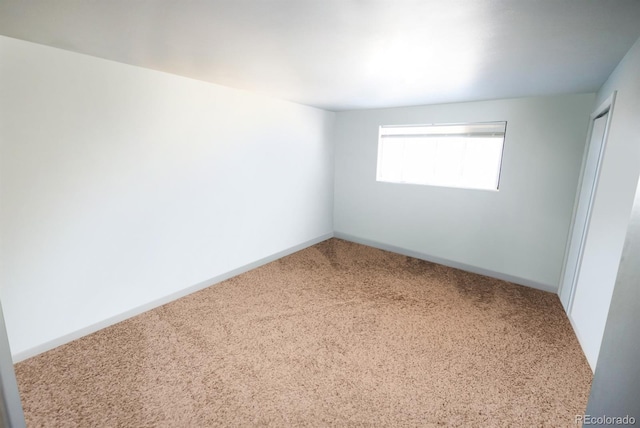 empty room featuring carpet and baseboards