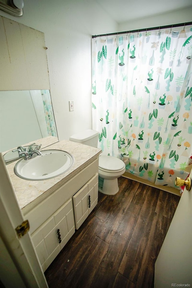 bathroom featuring toilet, shower / bath combo with shower curtain, wood finished floors, and vanity