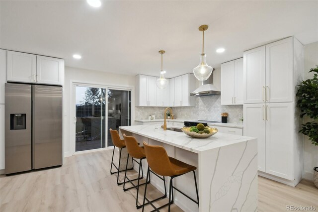 kitchen featuring white cabinetry, wall chimney exhaust hood, sink, and stainless steel refrigerator with ice dispenser