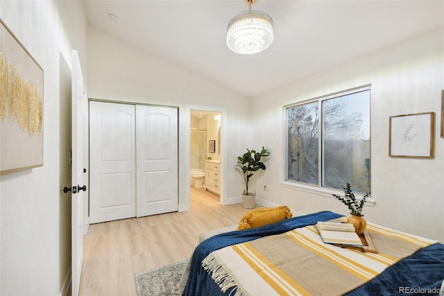 bedroom with light hardwood / wood-style floors, ensuite bath, and vaulted ceiling