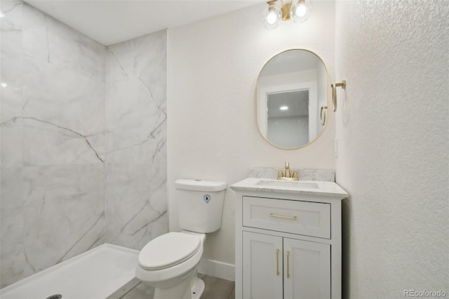 bathroom with toilet, vanity, and tiled shower