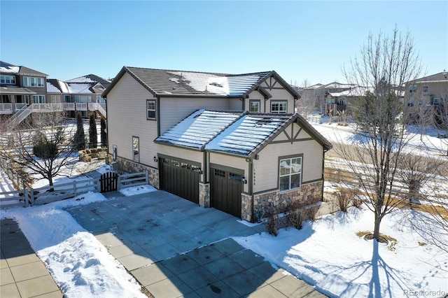 view of front of property with a tile roof, stone siding, and driveway