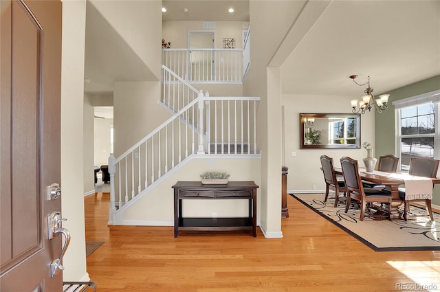 foyer featuring stairs, an inviting chandelier, baseboards, and light wood-type flooring