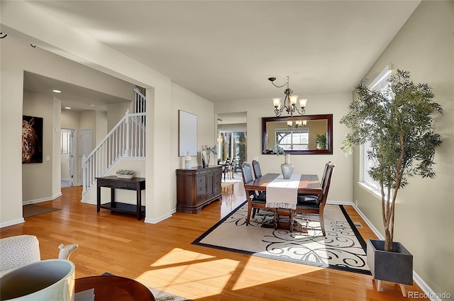 dining space featuring baseboards, stairs, light wood-type flooring, and an inviting chandelier