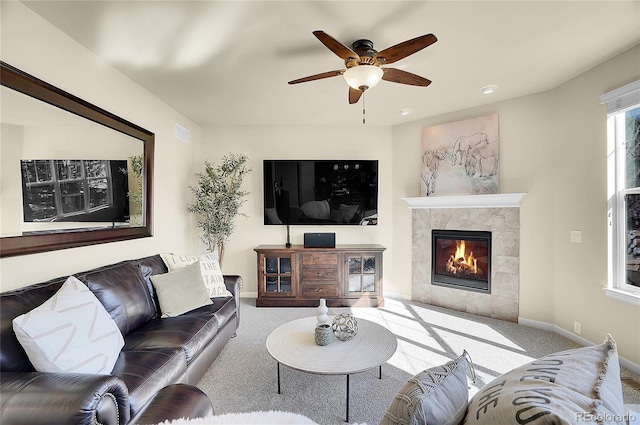 carpeted living area with baseboards, a fireplace, visible vents, and ceiling fan