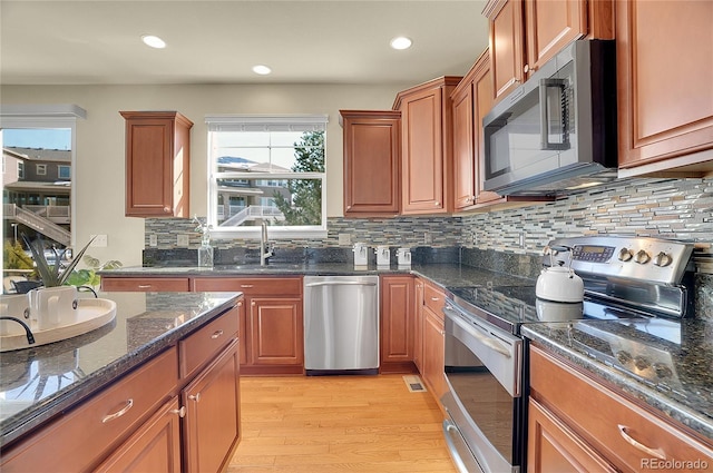 kitchen featuring a sink, tasteful backsplash, light wood-style floors, appliances with stainless steel finishes, and brown cabinetry