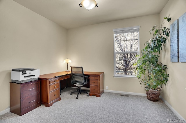 office space with baseboards, visible vents, and light carpet