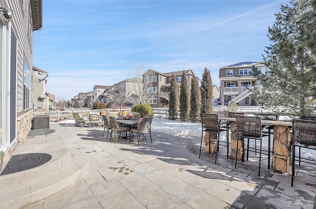 view of patio with outdoor dining area, central air condition unit, and a residential view