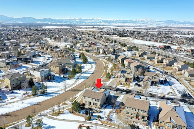 snowy aerial view featuring a mountain view and a residential view