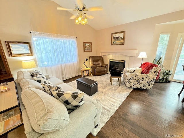 living room featuring ceiling fan, dark hardwood / wood-style floors, vaulted ceiling, and a tiled fireplace