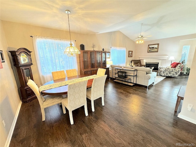 dining area featuring ceiling fan with notable chandelier, dark hardwood / wood-style floors, and vaulted ceiling