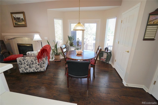 dining space featuring dark wood-type flooring and a tile fireplace