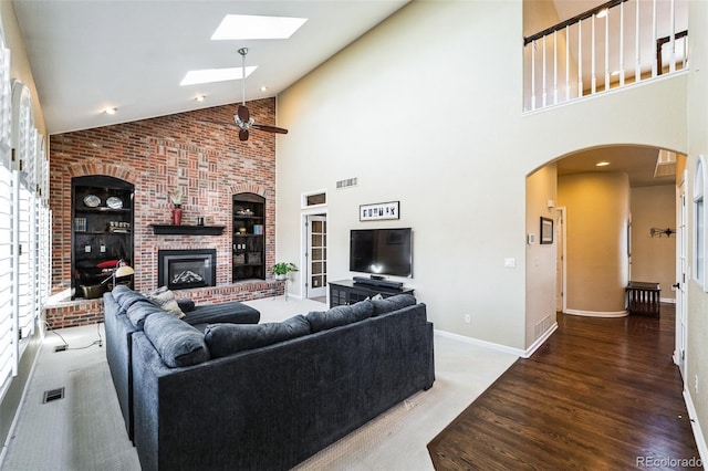 living area featuring wood finished floors, a skylight, a fireplace, and visible vents