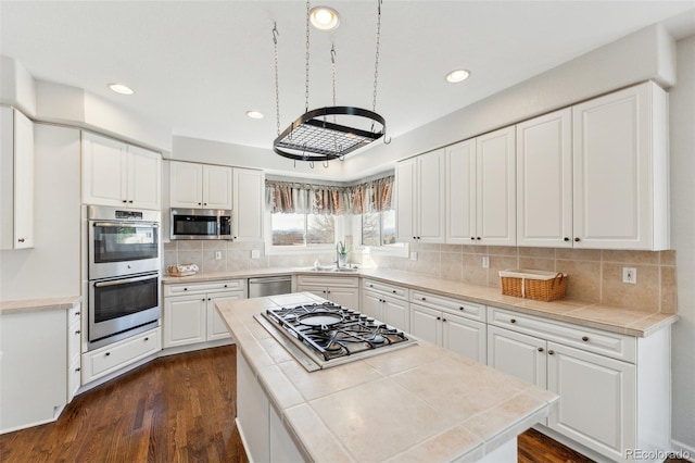 kitchen featuring dark wood finished floors, white cabinets, appliances with stainless steel finishes, and a sink