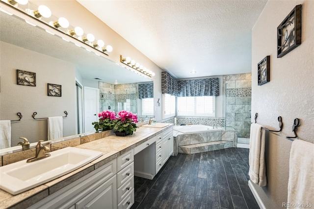 bathroom featuring a textured wall, a tile shower, wood finished floors, a textured ceiling, and a sink