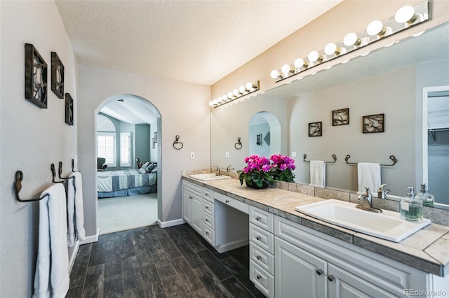 full bathroom with wood tiled floor, double vanity, ensuite bathroom, and a sink