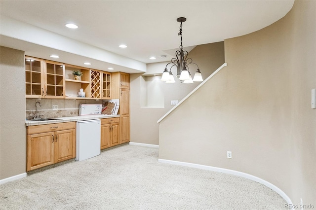 kitchen featuring a sink, baseboards, dishwasher, and light carpet