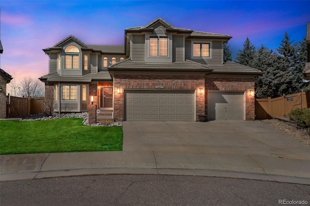 traditional-style home featuring brick siding, a garage, a front yard, and fence