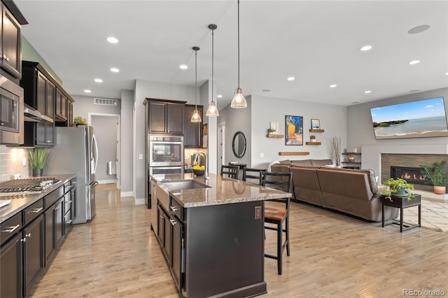 17358 W 95th Ave, Arvada, CO 80007 - kitchen featuring stainless steel appliances, a kitchen bar, light stone counters, light wood-style floors, and tasteful backsplash