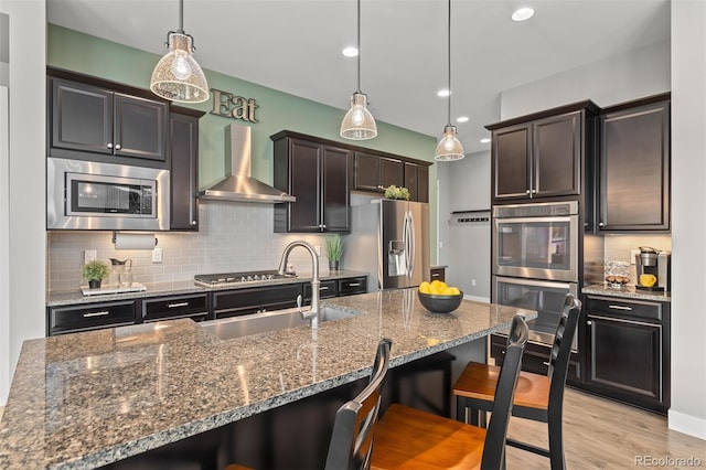 17358 W 95th Ave, Arvada, CO 80007 - kitchen featuring stainless steel appliances, wall chimney range hood, a breakfast bar area, backsplash, and recessed lighting